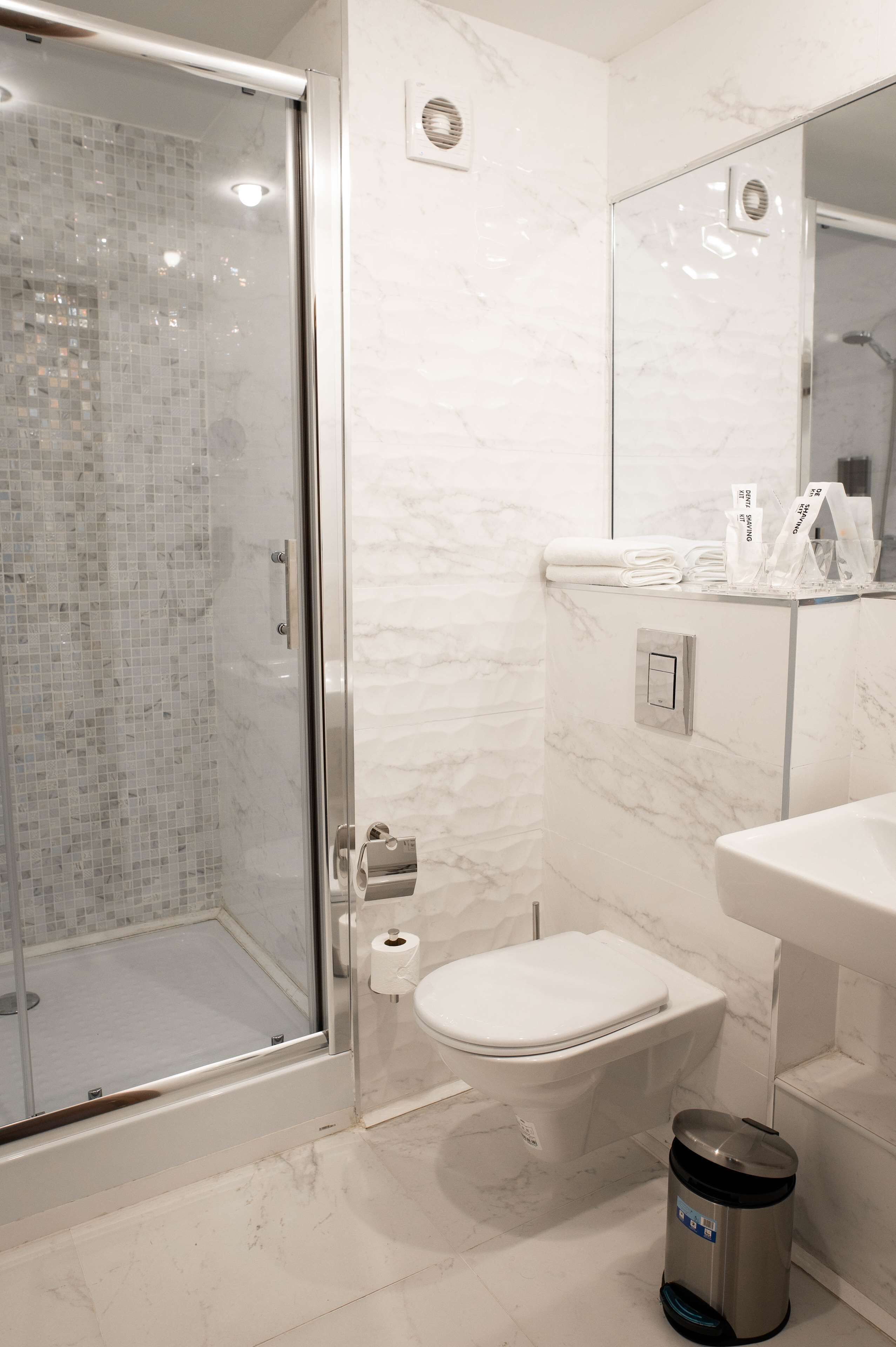 A modern bathroom with a glass-enclosed shower, a toilet, and a sink.