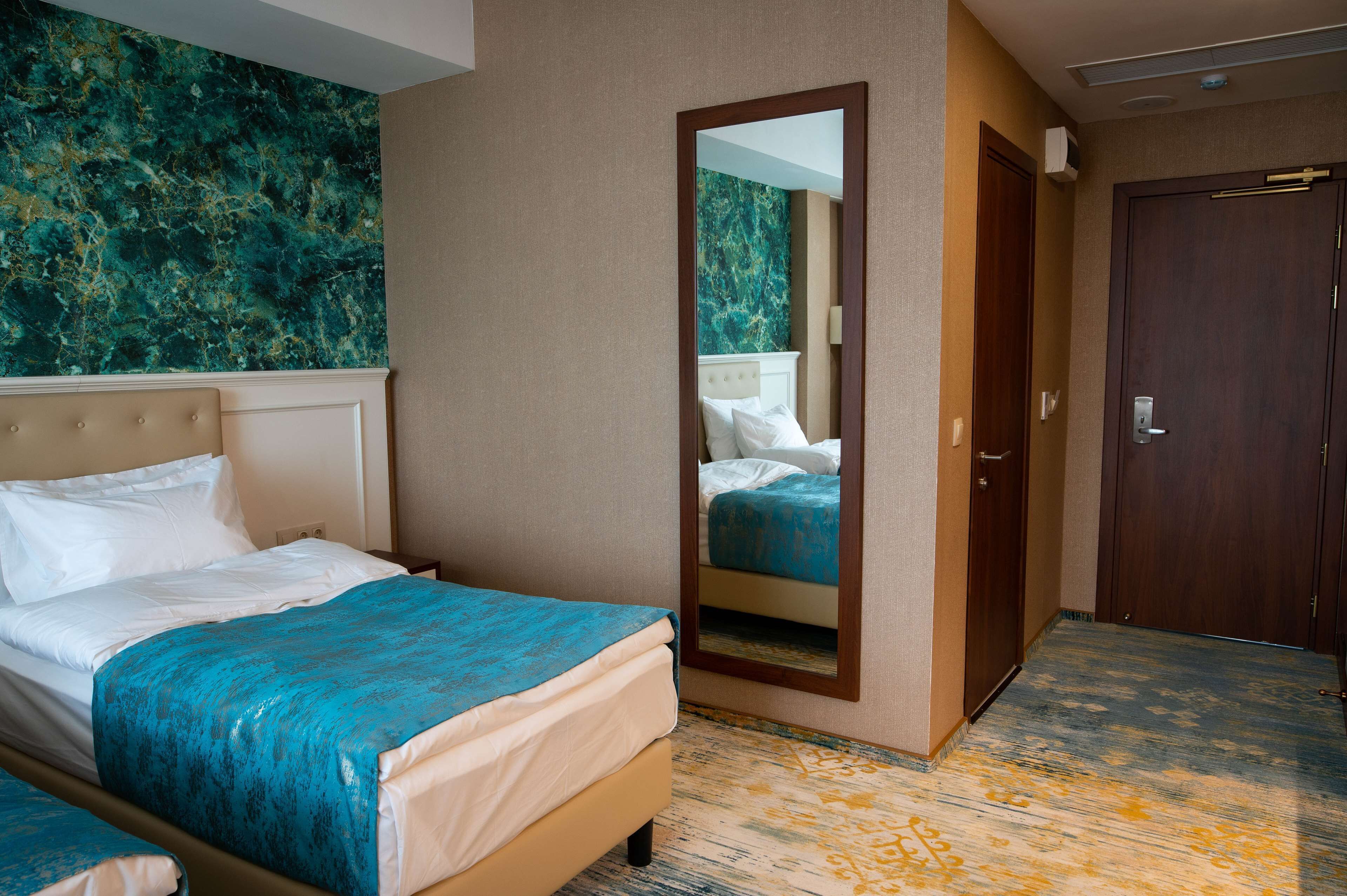 Ein Hotelzimmer mit einem Bett, einem Spiegel, einem Kleiderschrank und einer Wand mit Marmormuster.