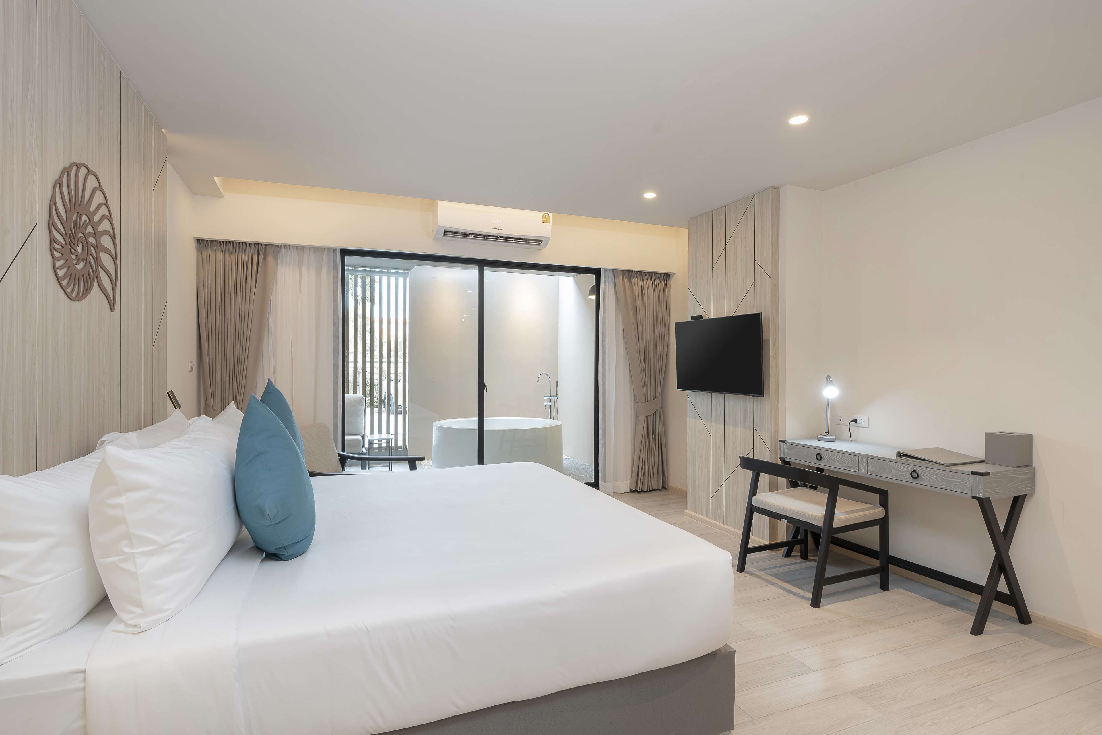 Quarto de hotel moderno com uma cama grande, uma escrivaninha e uma televisão.