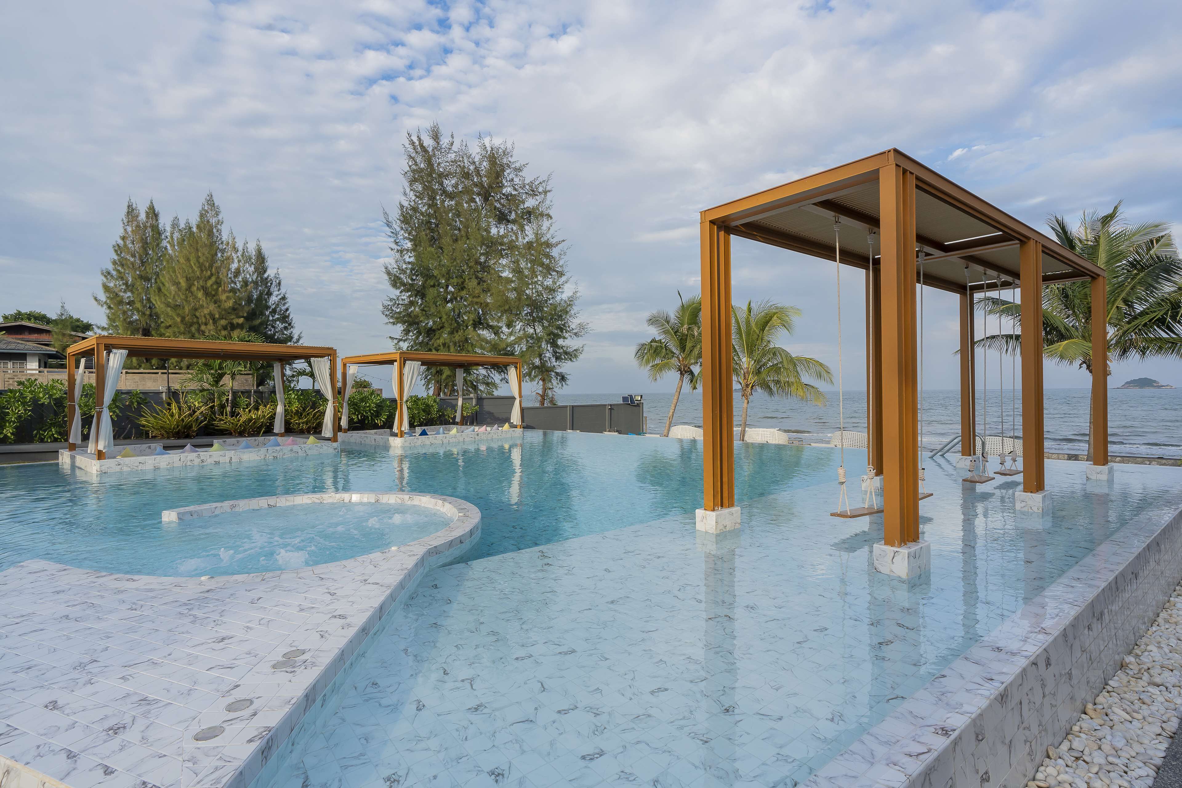 A swimming pool with a wooden pergola and a view of the sea.