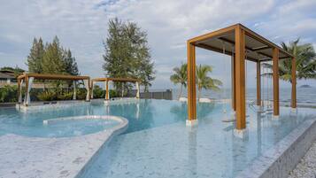 A swimming pool with a wooden pergola and a view of the sea.