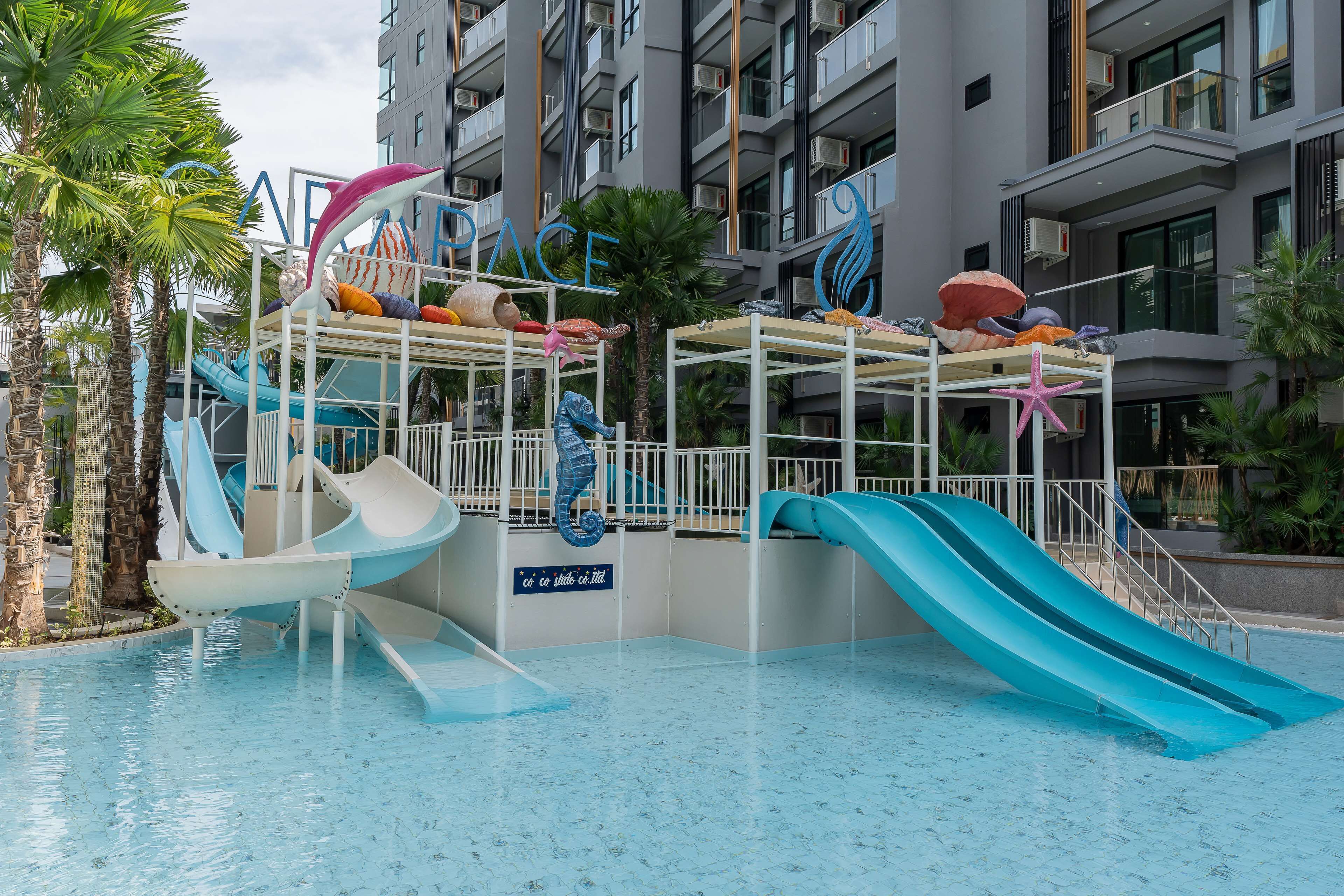 Zona de piscina con toboganes, palmeras y un letrero que dice "PACE".