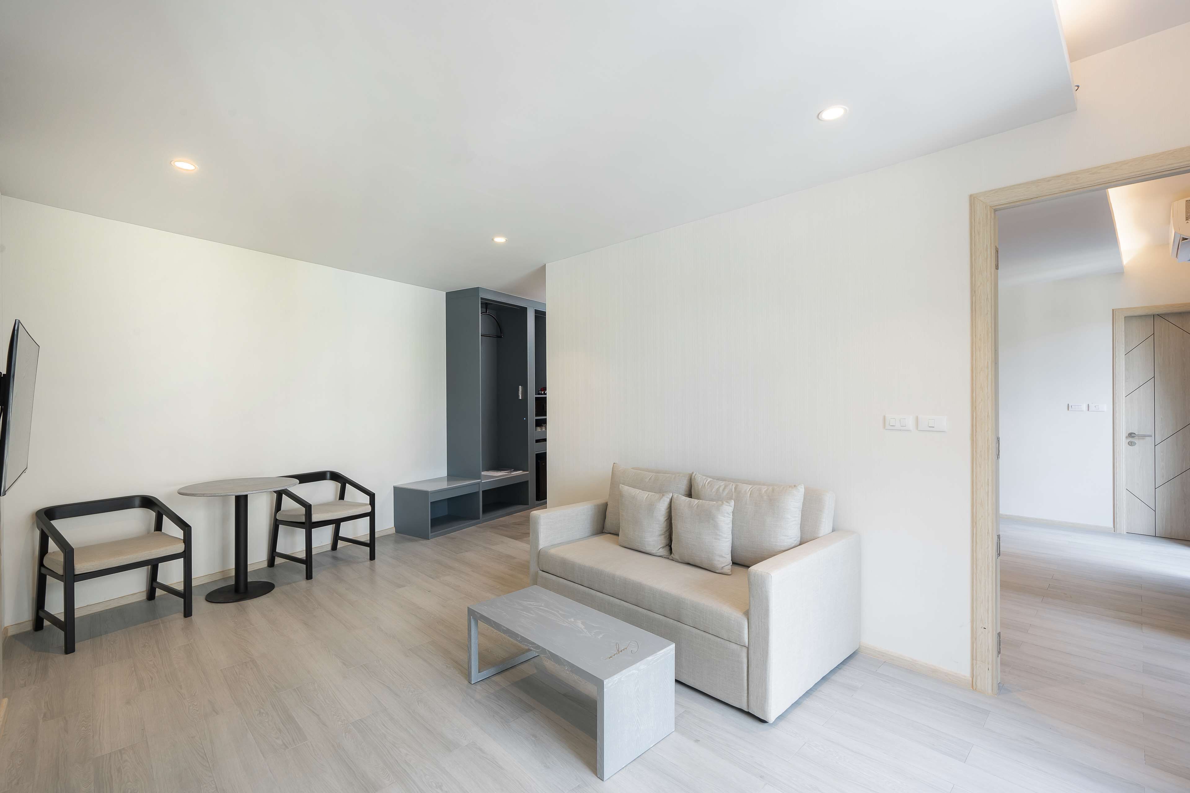 A modern living room with a sofa, two armchairs, a coffee table, and a TV.