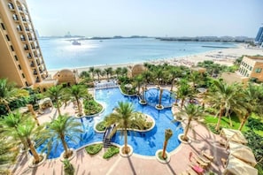 Relax by the pool surrounded by lush gardens and palm trees, with access to the beach and stunning sea views.