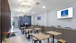 Un moderno vestíbulo de hotel con mesas y sillas de madera, una recepción y un cartel que indica que es el Best Western Victoria Market Hotel.