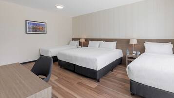 A hotel room with two beds, a desk, and a chair.