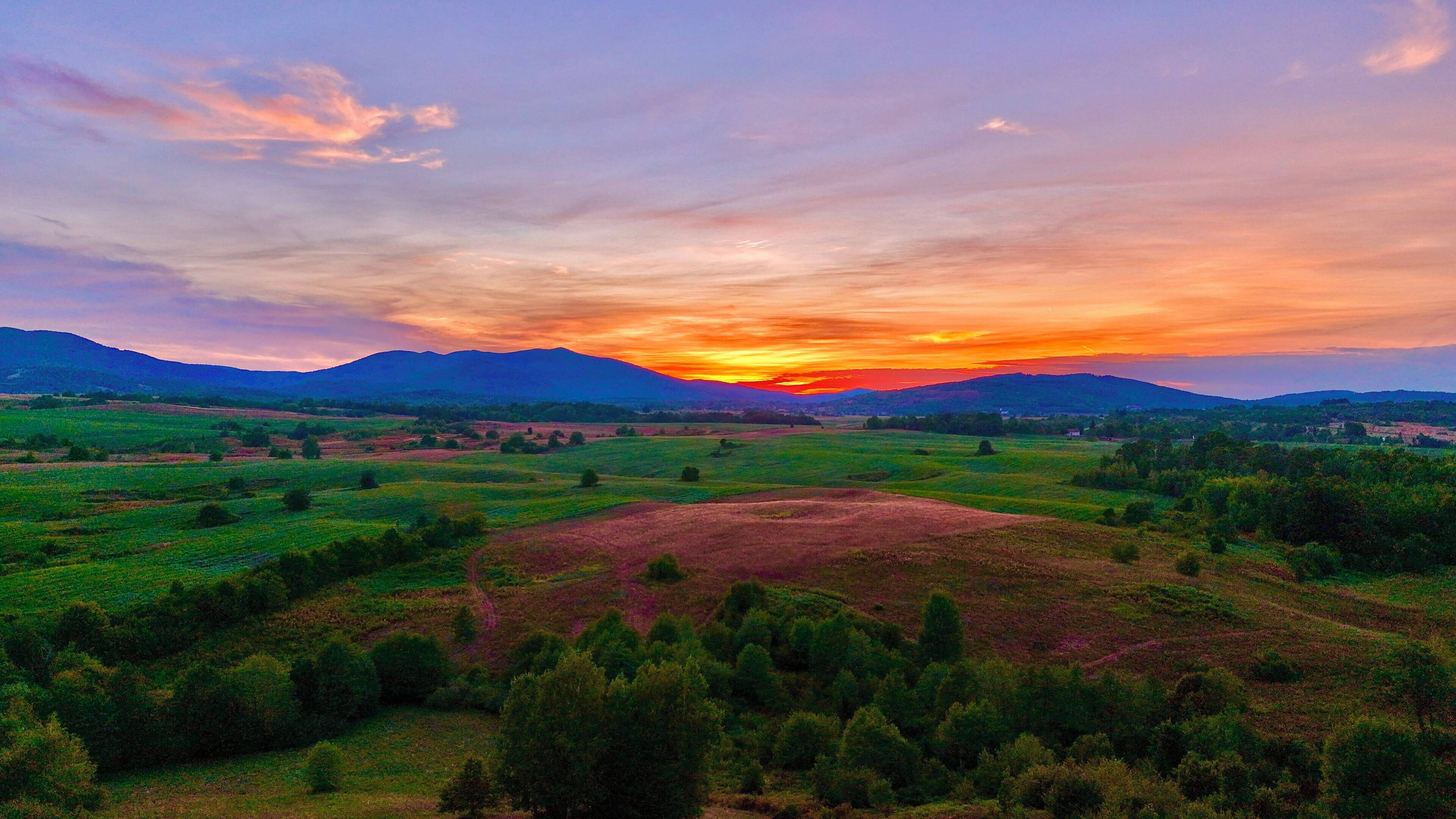 A panoramic view of a mountainous landscape with a sunset.