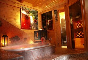 A wooden interior with a stone-tiled bathtub, wooden walls, and a staircase.