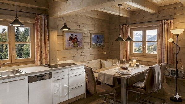 Ein Holzblockhaus-Interieur mit Küche, Essbereich und großen Fenstern.