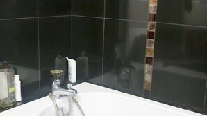 A bathroom with a white sink, a mirror, and a shower area. - Charme Belfort CityCosy (Vincennes)