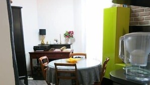 A compact kitchen with a round dining table, wooden chairs, a green cabinet, and a black countertop. - Charme Belfort CityCosy (Vincennes)
