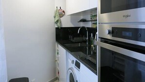 A compact kitchen with a washing machine, a microwave, and a dishwasher. - Charme Belfort CityCosy (Vincennes)
