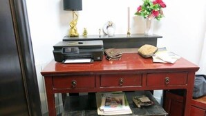 A wooden desk with a printer, a lamp, a vase with flowers, and various items on it. - Charme Belfort CityCosy (Vincennes)