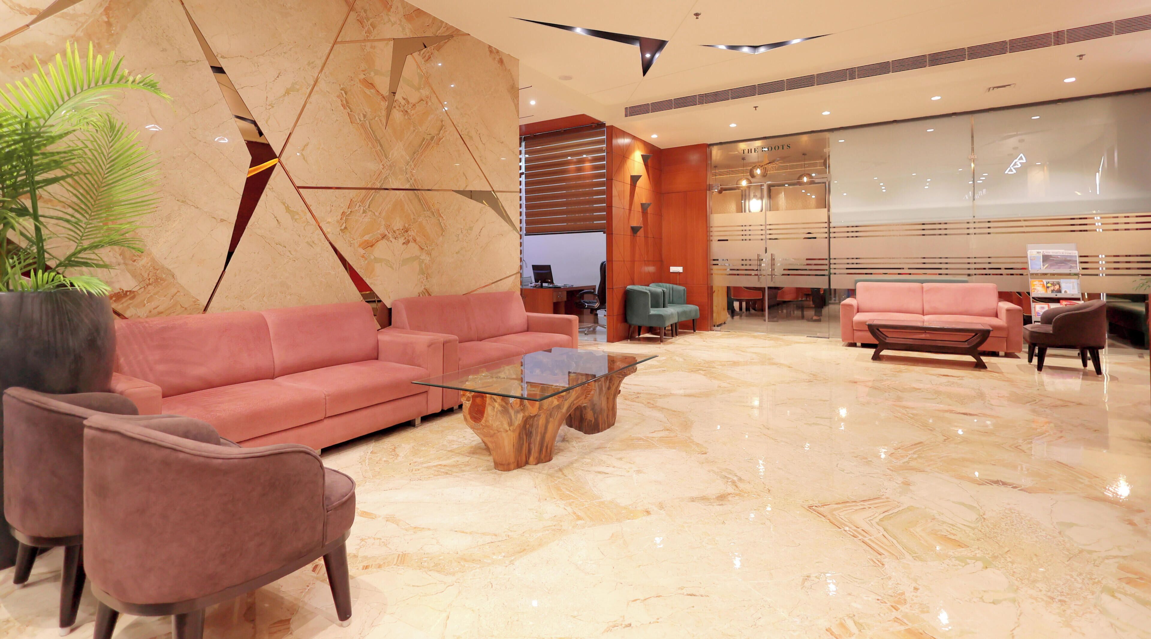 Una hall moderna con pavimento in marmo, un divano rosa, un tavolino da caffè in vetro e una scrivania della reception.