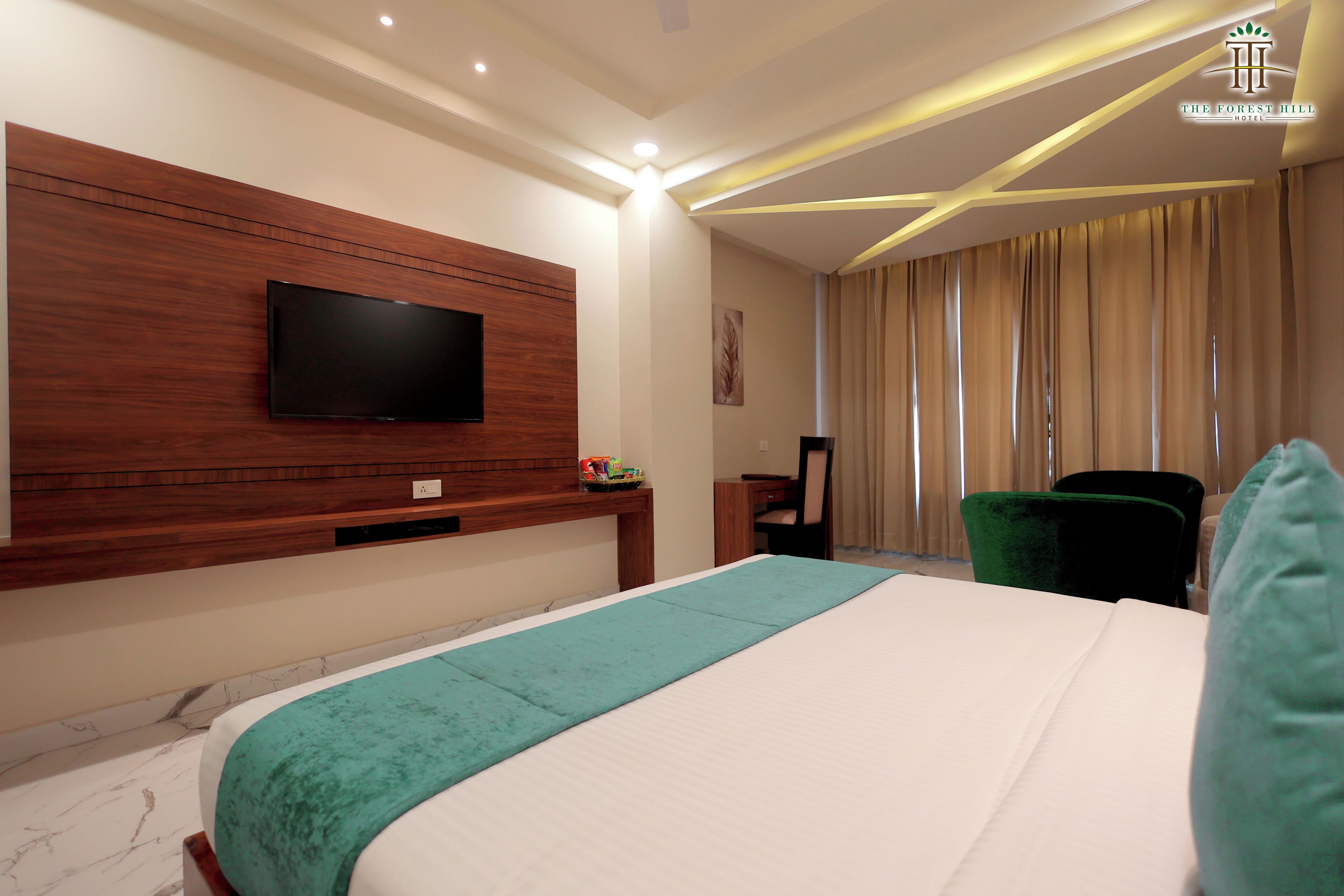 A hotel room with a large bed, a TV mounted on a wooden panel, a desk, and a chair.
