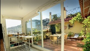 A sunlit patio with a dining area, large windows, and a view of the cityscape. - Le terrazze di Chiaia is a charming penthouse with two large panoramic terraces (Napoli)