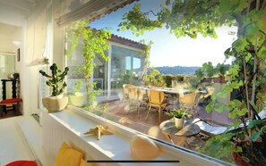 A balcony with a dining area, potted plants, and a view of the cityscape.
