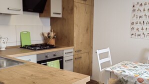 Une cuisine moderne avec des meubles en bois, une cuisinière à gaz et un coin repas comprenant une table et des chaises.