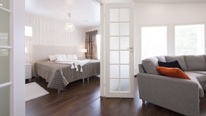 Un dormitorio con cama, mesita de noche, cómoda y ventana grande.