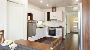 Una cocina moderna con armarios blancos, electrodomésticos de acero inoxidable y una mesa de comedor de madera.
