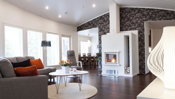 Una sala de estar moderna con chimenea, un sofá con cojines, un comedor y una lámpara de techo original.