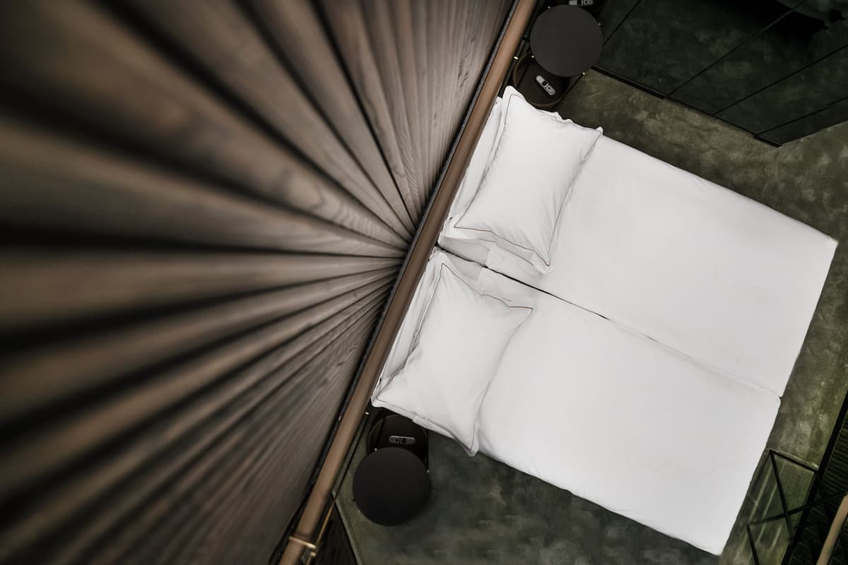 Ein Zimmer mit einem Bett, einem runden schwarzen Hocker und einem schwarzen Tisch.