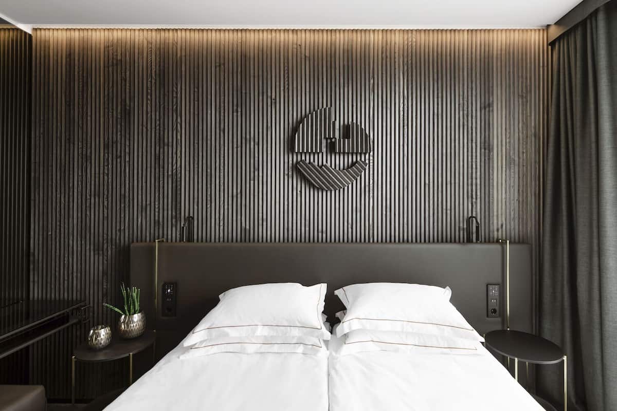 Ein modernes Hotelzimmer mit einem großen Bett, Nachttischen und einem einzigartigen Kunstwerk an der Wand.