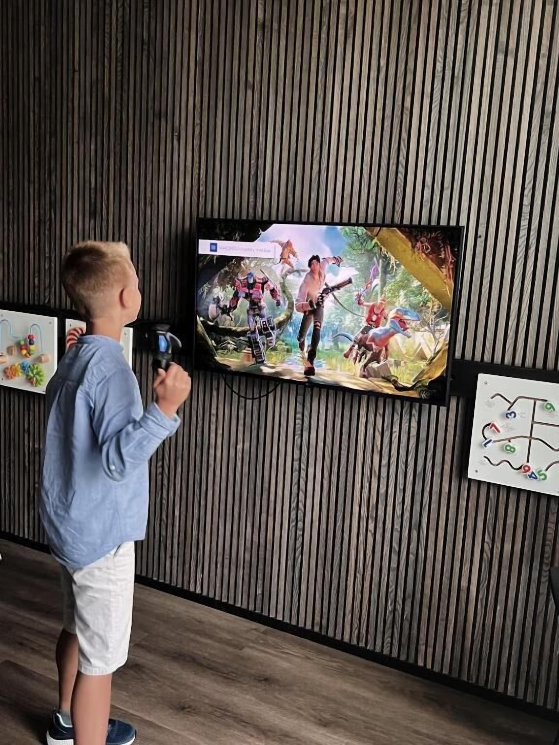 A child playing a video game in front of a television mounted on a wooden wall.