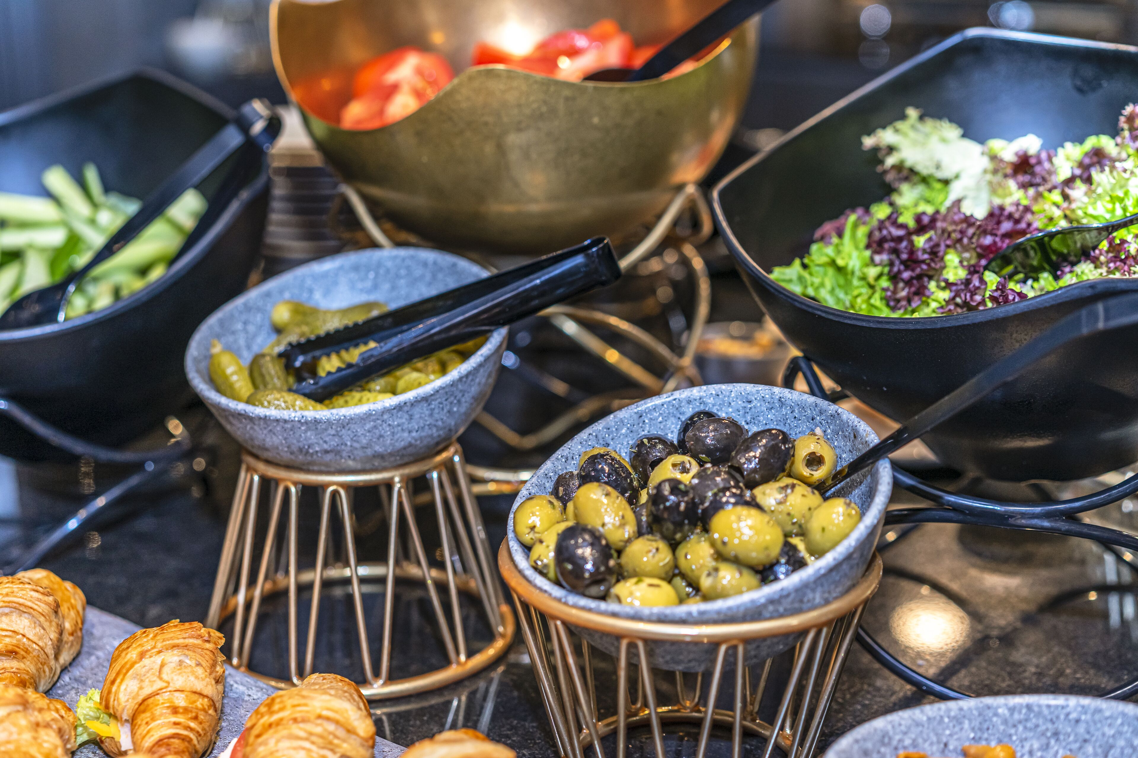 Un buffet con diverse portate, tra cui olive, verdure e dolci.
