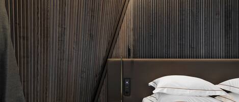 A modern bedroom with a wooden panel wall, a bed with white bedding, and a small round table.