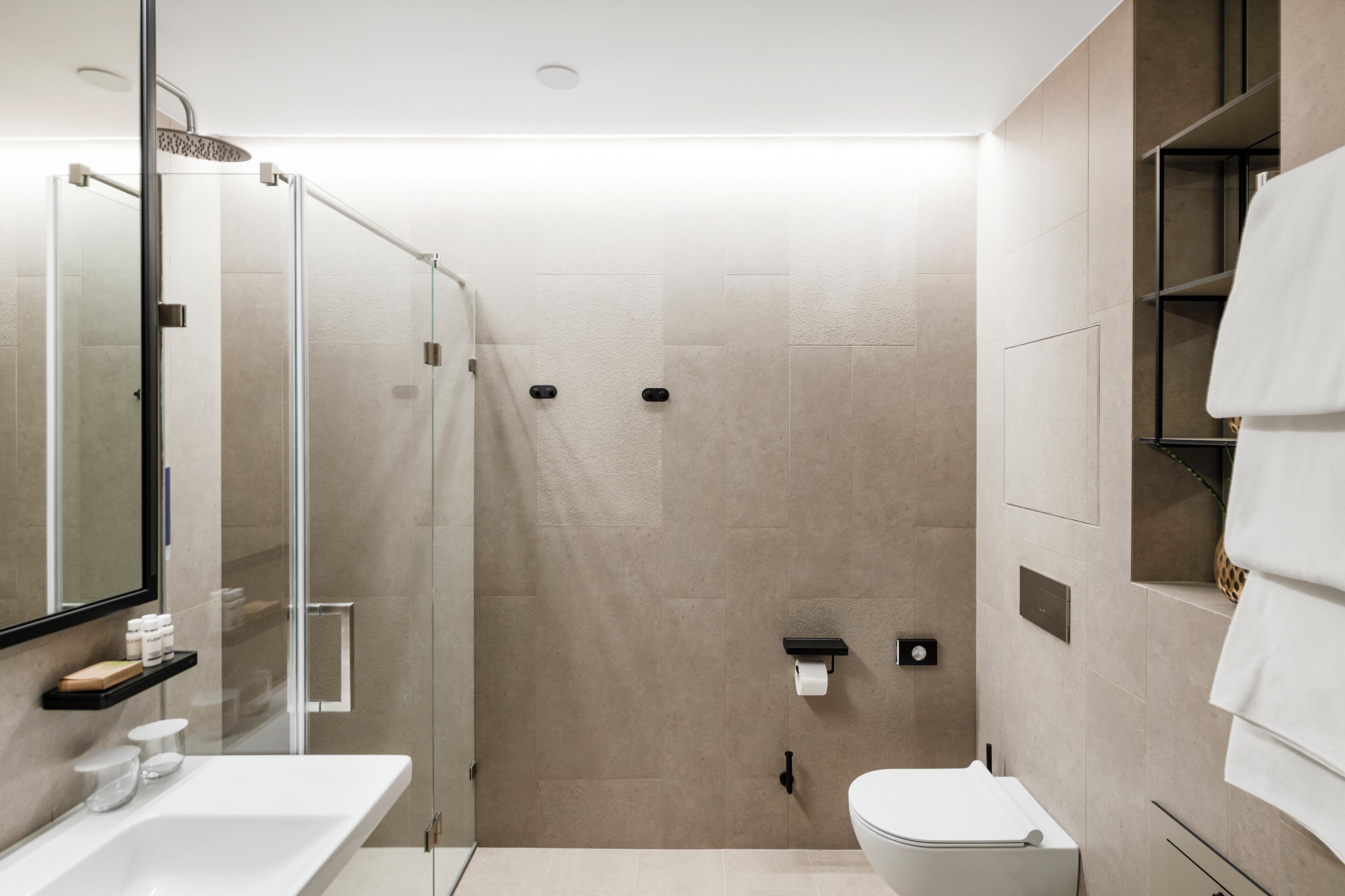 Un baño moderno con ducha de vidrio, lavamanos blanco y retrete.