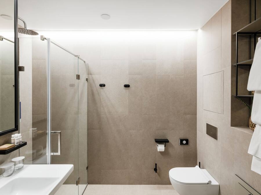 A modern bathroom with a glass-enclosed shower, a white sink, and a toilet.