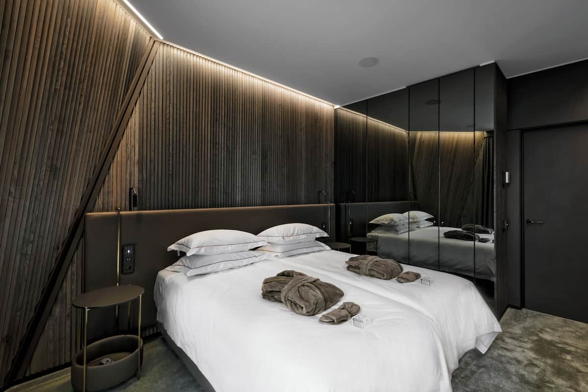Ein modernes Schlafzimmer mit einem großen Bett, einem Nachttisch, einem Spiegel und einem Kleiderschrank.
