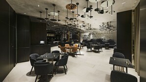 A modern restaurant with black and white decor, multiple dining tables, and hanging pendant lights. - MANA Sleep & SPA (Druskininkai)