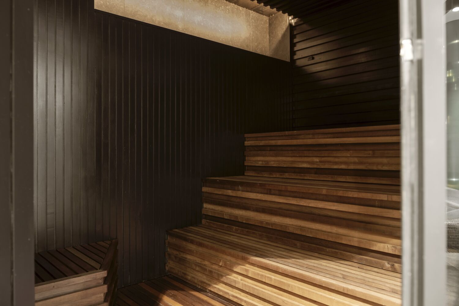 Una escalera de madera con una pared oscura y un suelo de madera clara.