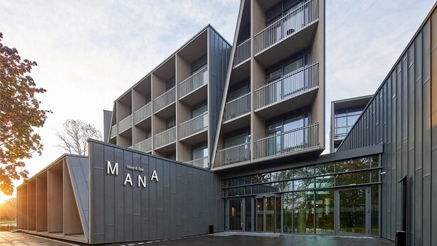 A modern building with a prominent 'MANANA' sign, featuring multiple balconies and large glass windows. - MANA Sleep & SPA (Druskininkai)