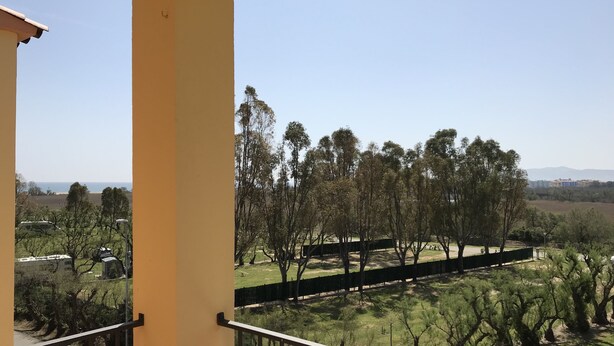 A balcony with a view of a park and distant buildings. - Apartment l'Estartit beach (Torroella de Montgrí)