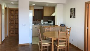 A modern kitchen with wooden cabinets, a dining table with chairs, and a microwave. - Apartment l'Estartit beach (Torroella de Montgrí)