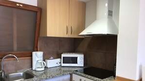 A compact kitchen with a washing machine, microwave, toaster, and sink. - Apartment l'Estartit beach (Torroella de Montgrí)