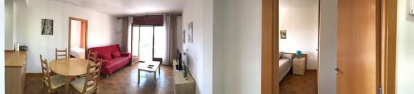 A living room with a red sofa, a wooden dining table, and a TV. - Beach Apartment in L'Estartit (Torroella de Montgrí)