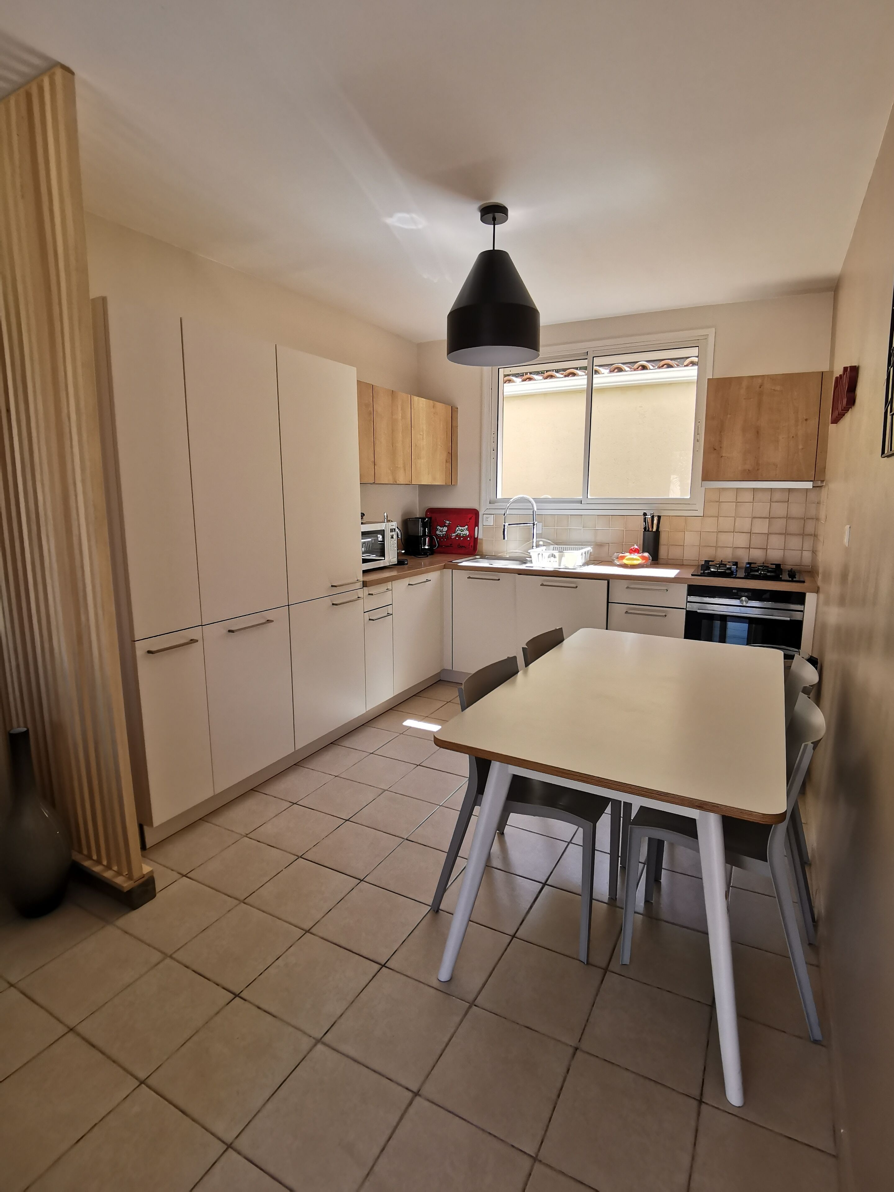 A kitchen with a dining table, cabinets, a microwave, a coffee maker, and a window.