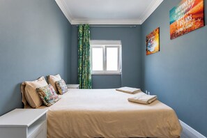 A bedroom with a bed, a nightstand, a window, and a curtain.