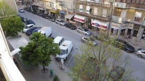 Une vue d’une rue avec des voitures garées, un fourgon blanc et un bâtiment sur lequel on peut lire l’inscription « ARMAZENS ».