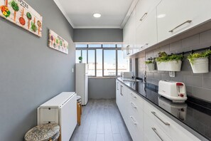 Een moderne keuken met grijze wanden, witte kasten, een zwart aanrecht en een raam voor natuurlijk lichtinval.