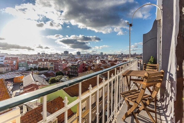 Private balcony with outdoor seating and an open view across Lisbon’s rooftops.
