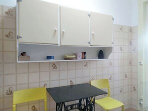 A small room with a table and two chairs, a cabinet above the table, and a tiled wall with animal patterns.
