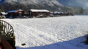 A snow-covered landscape with a building featuring multiple windows and a sloped roof, surrounded by mountains. - 2-room apartment with balcony in Samoëns, parking included (Samoëns)