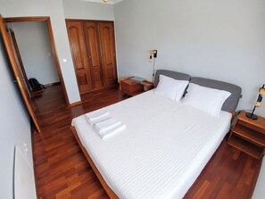 Une chambre d’hôtel avec un grand lit, une armoire en bois, des tables de chevet et un miroir.