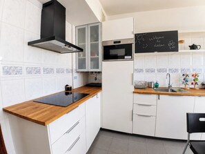 Une cuisine moderne avec des meubles blancs, une cuisinière noire et un tableau noir sur lequel on a écrit : « Bienvenue à Lisbonne ».