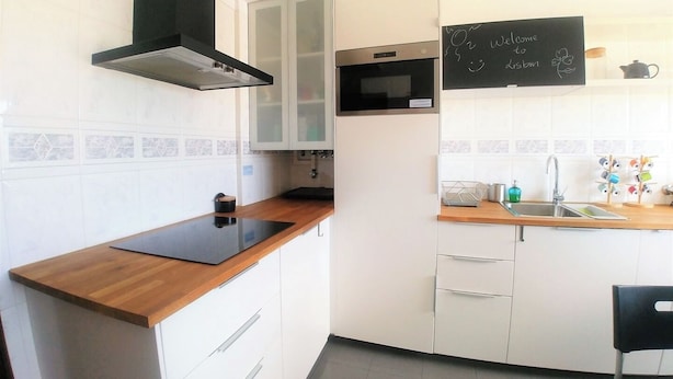 Una cocina moderna con armarios blancos, una campana extractora negra, un microondas y una pizarra con un mensaje de bienvenida.